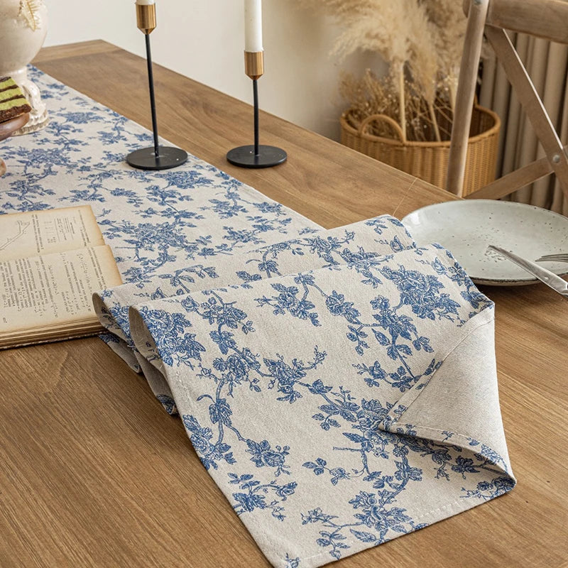 A blue and white floral patterned checkered table runner laid on a wooden table.