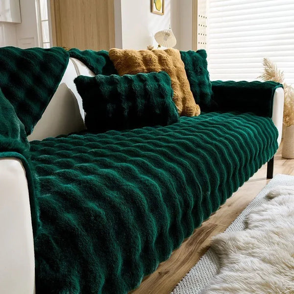 A deep emerald green plush rabbit sofa cushion draped over a white sofa.