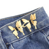 Gold fabric butterfly brooches pinned onto a blue denim jean pocket