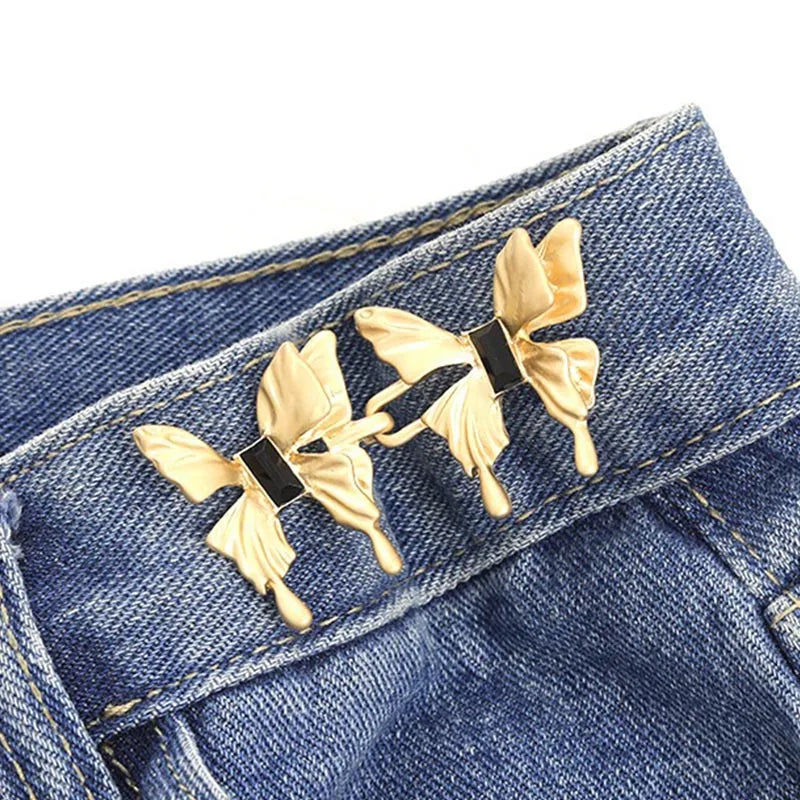 Gold fabric butterfly brooches pinned onto a blue denim jean pocket