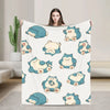 A woman holds up a white plush decorative throw blanket featuring cute blue and yellow animal characters.