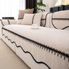 A beige pleated sofa cover with black trim and textured fabric displayed on a white sofa.