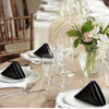 A close-up of black silky satin dinner napkins and silverware set on a table for an event.
