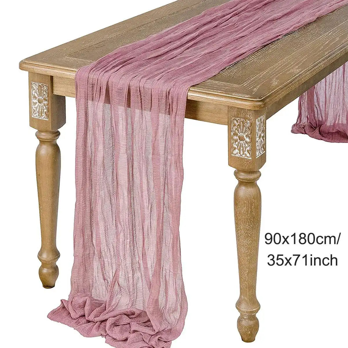 A pink semi-sheer gauze fabric draped elegantly over a wooden table.