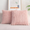 A pink faux rabbit fur cushion cover is displayed on a light-colored sofa next to a framed artwork.
