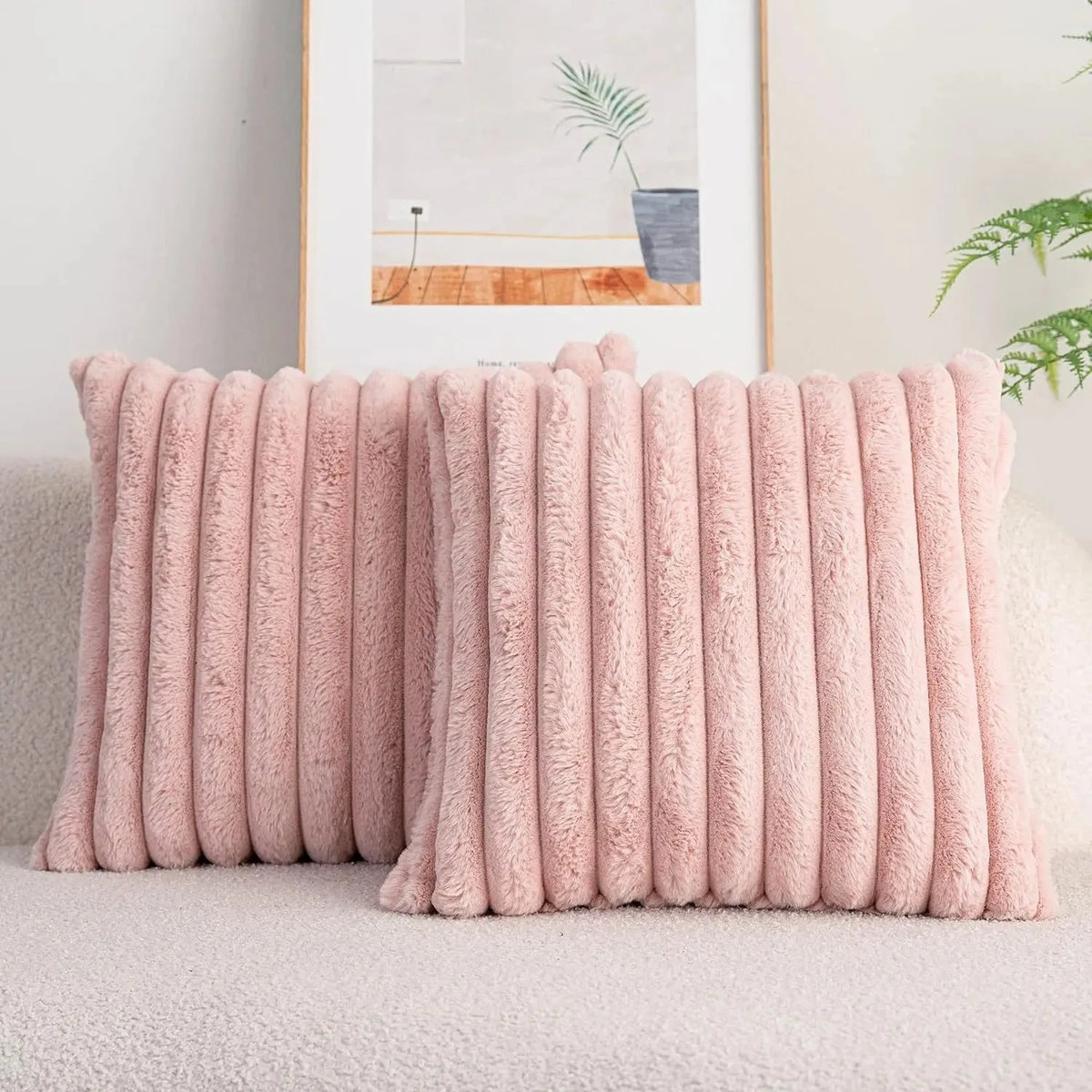 A pink faux rabbit fur cushion cover is displayed on a light-colored sofa next to a framed artwork.