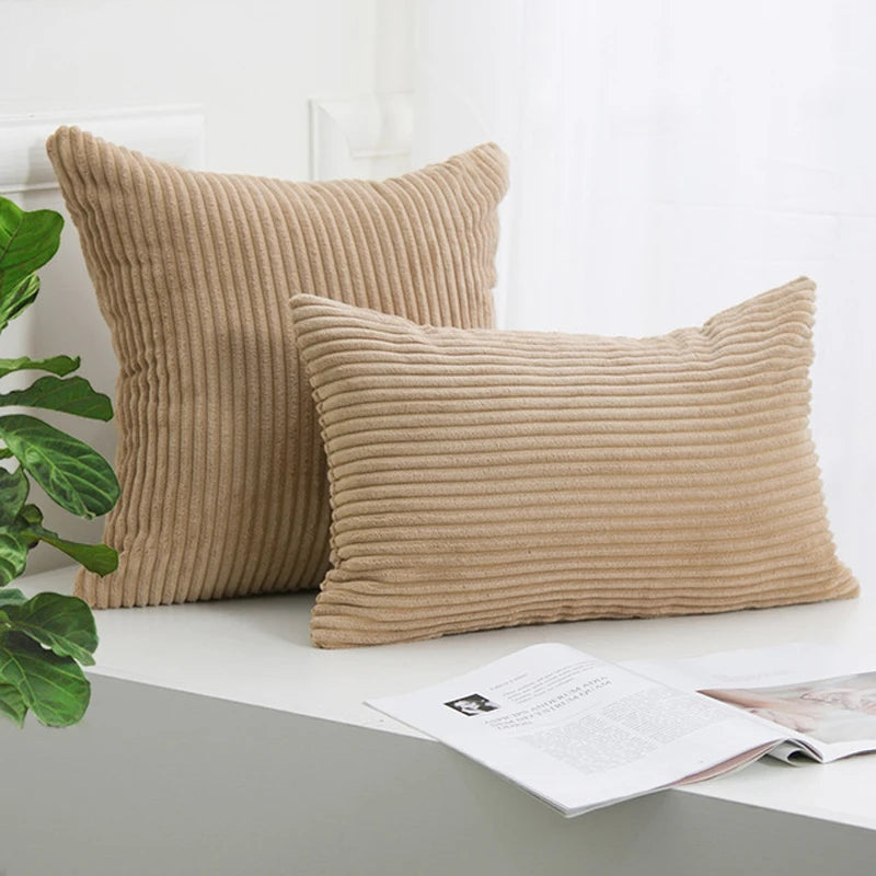 Two beige corduroy striped throw pillows resting on a white surface.
