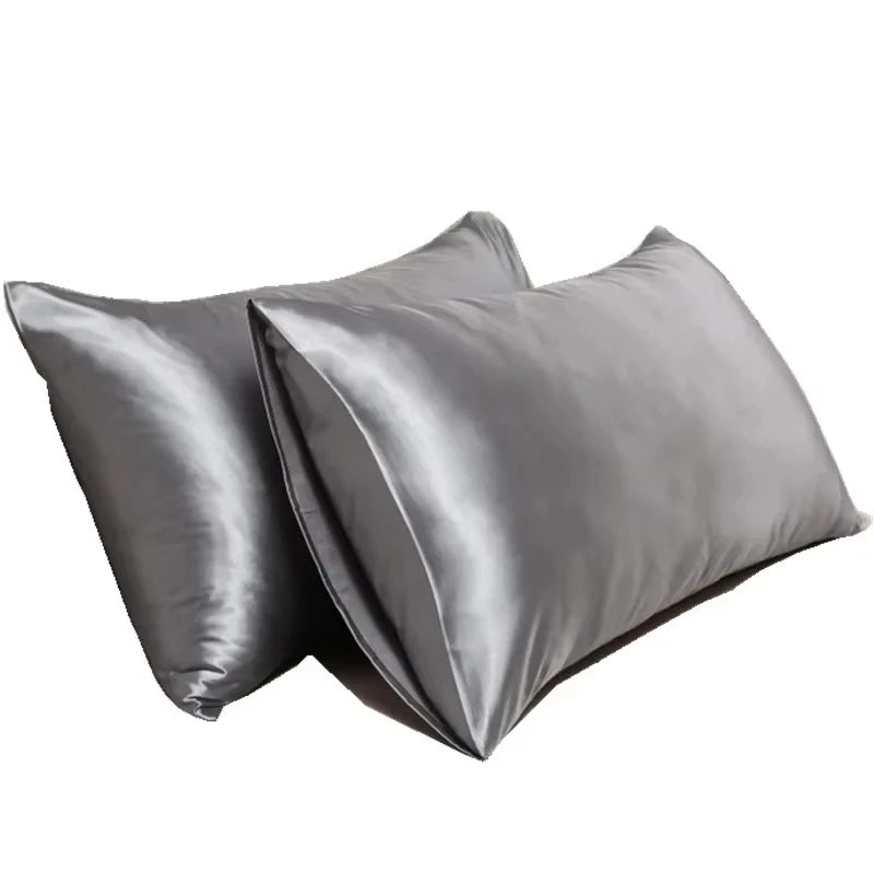 Two smooth gray satin silk pillow covers folded on a white background.
