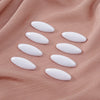 Eight white plastic safety pins arranged on a pink fabric background.