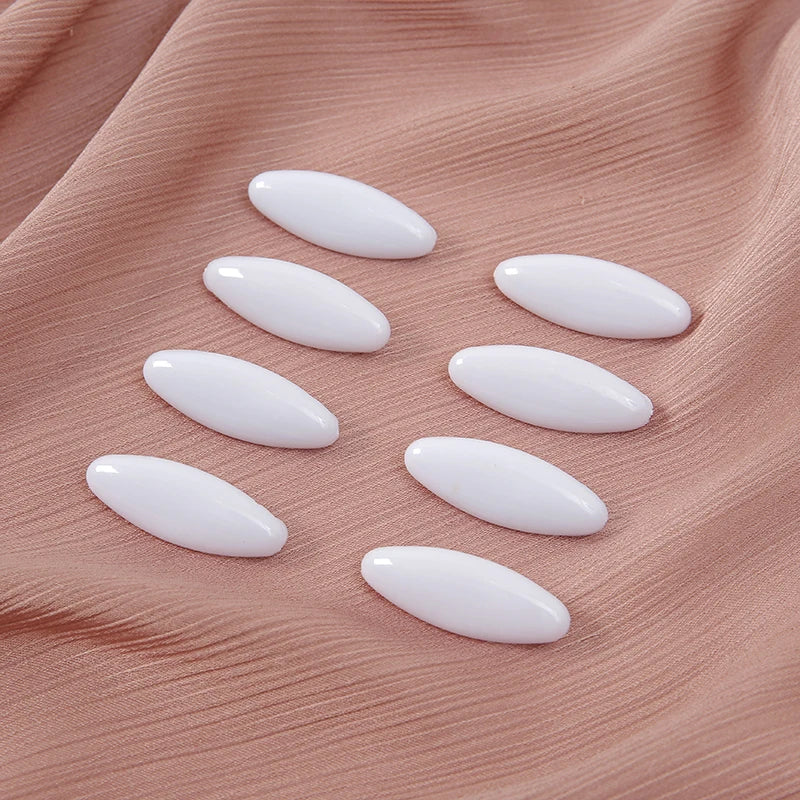 Eight white plastic safety pins arranged on a pink fabric background.