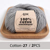 Gray organic cotton yarn skeins labeled QJH 100% COTON ORGANIQUE on a wooden tray