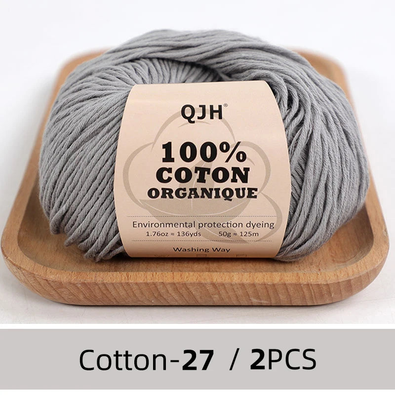 Gray organic cotton yarn skeins labeled QJH 100% COTON ORGANIQUE on a wooden tray
