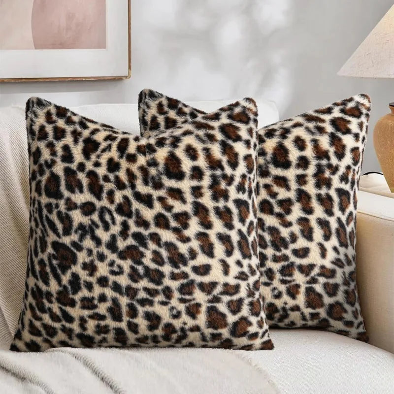 Three leopard print velvet pillow covers resting on a light-colored sofa.