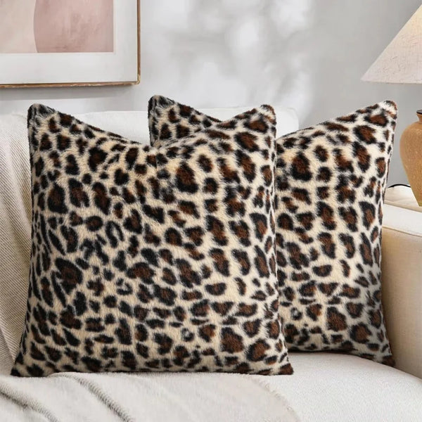 Three leopard print velvet pillow covers resting on a light-colored sofa.