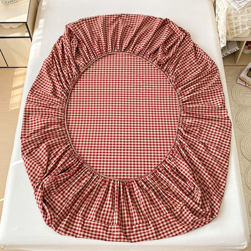 A red and white checkered fitted sheet laid out on a white surface.