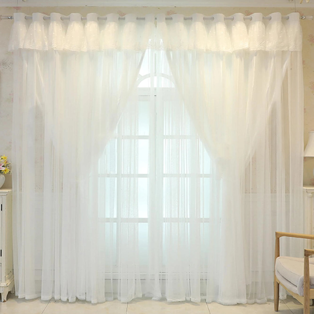 White sheer double-layer curtains covering a large window with a pointed arch shape