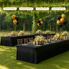 A long black rectangular table set for an outdoor family gathering with floral arrangements and balloons.