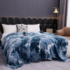 A deep blue and white tie-dye flannel fleece throw blanket draped over a bed.
