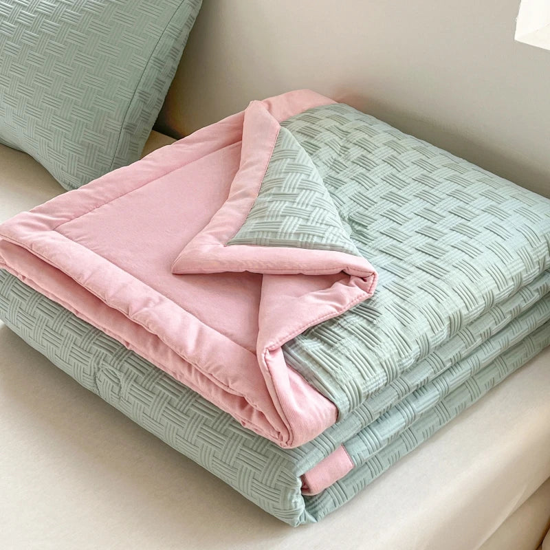 Pink and mint green breathable waffle quilt folded on a light-colored surface.