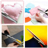A hand holds stainless steel zig zag lace sewing scissors next to a piece of fabric and colored paper.