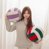 A young woman holds a purple and white striped plush volleyball ball cushion.