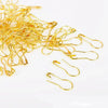 A pile of thin, gold-colored safety bulb pins for knitting and sewing.