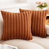 Two brown faux rabbit fur cushion covers standing upright on a light-colored sofa.