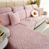A pink plush velvet sofa cover with a quilted texture and anti-slip backing is displayed on a light-colored sofa.
