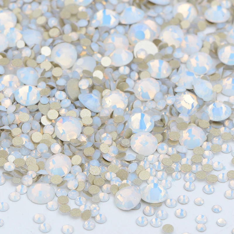 A pile of clear glass rhinestones in various sizes and shades of silver and iridescent blue for DIY crafts