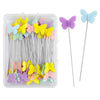 A clear plastic box containing dressmaking pins with colorful butterfly heads in purple and light blue.
