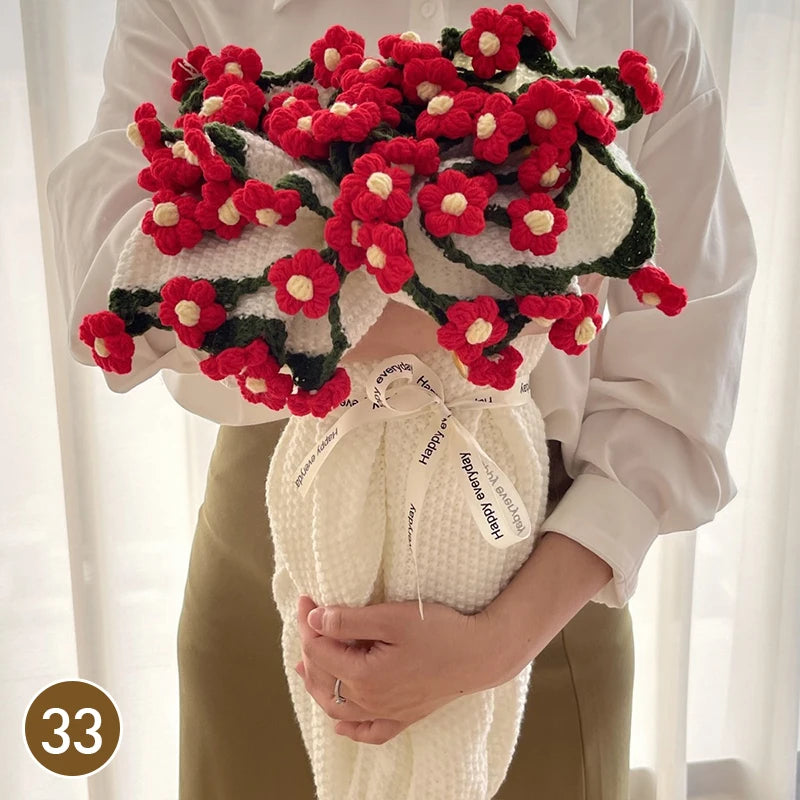 A hand knitted floral rose bouquet throw blanket featuring red and green yarn flowers.