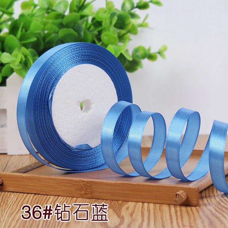 Rolls of satin ribbon in various shades of blue and light blue on a wooden surface