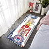 A rectangular floor mat featuring a portrait and text on a white background placed on a dark floor.