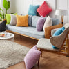 A cozy living room scene featuring various striped velvet corduroy cushion covers on a sofa and floor cushions.
