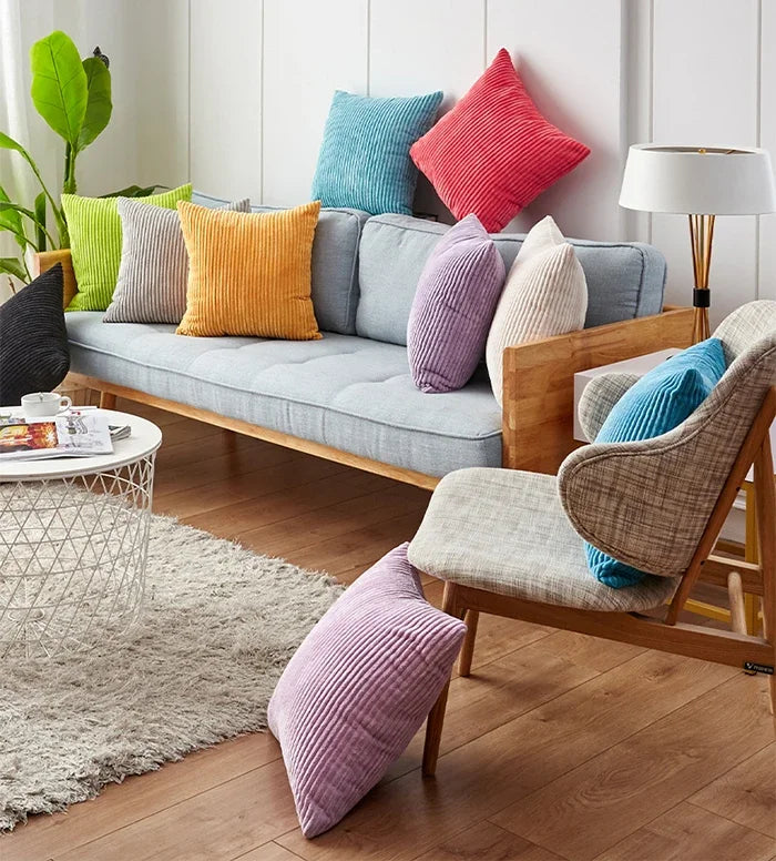 A cozy living room scene featuring various striped velvet corduroy cushion covers on a sofa and floor cushions.