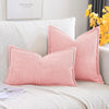 A pink striped corduroy lumbar support pillow cushion resting on a white sofa.