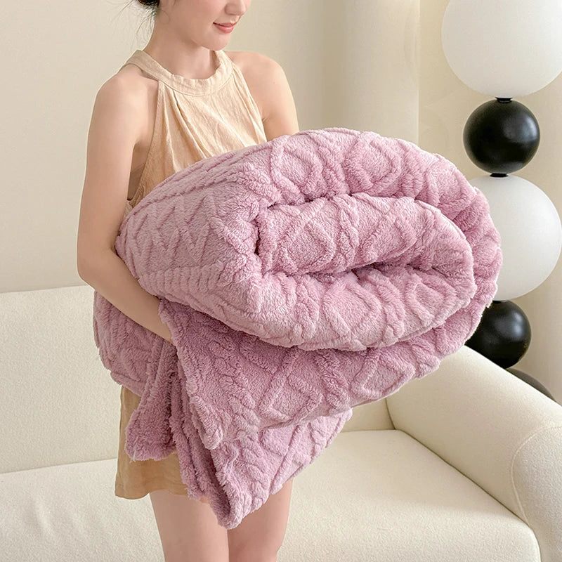 A woman is holding a fluffy pink coral fleece blanket in a relaxed pose.