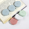 A collection of various colored retractable double-sided measurement tapes displayed on a light-colored book.