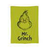 A lime green throw blanket featuring a black line drawing of a grumpy-looking bird with spiky feathers and the text Mr. Grinc