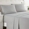 A set of gray microfiber bed sheets and pillows on a bed with a tufted headboard.