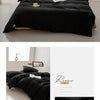 A black minimalist duvet cover with a simple design displayed on a bed.