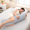 A woman lies on a white bed using a light blue ergonomic double wave curve pillow for support.