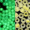 A close-up view of a 600-pack of 3mm glow-in-the-dark glass seed beads in various shades of green and yellow.