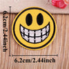 Yellow embroidered patch featuring a wide, toothy, smiling face emoji design