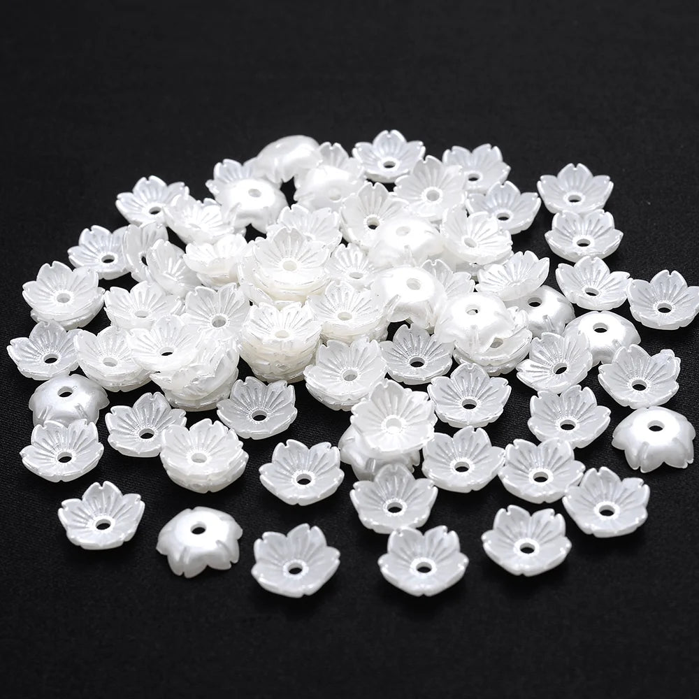 A pile of small white imitation pearl flower spacer beads for DIY jewelry