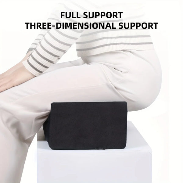 A person is sitting with a black ergonomic seat cushion placed on their lap, demonstrating three-dimensional support.