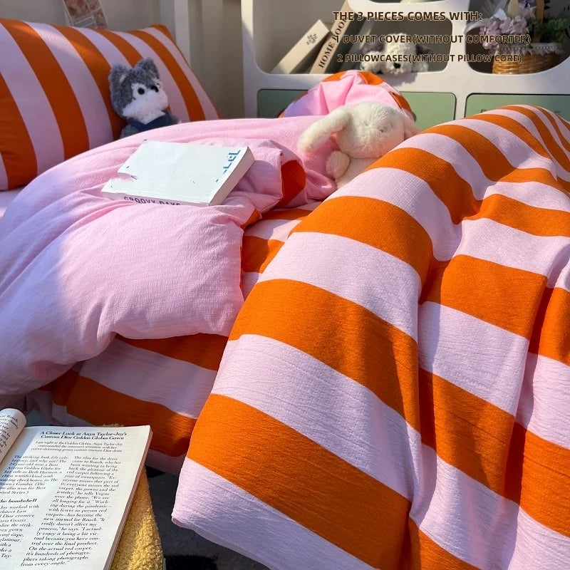 A pink and orange striped duvet cover set displayed on a bed with a stuffed animal.