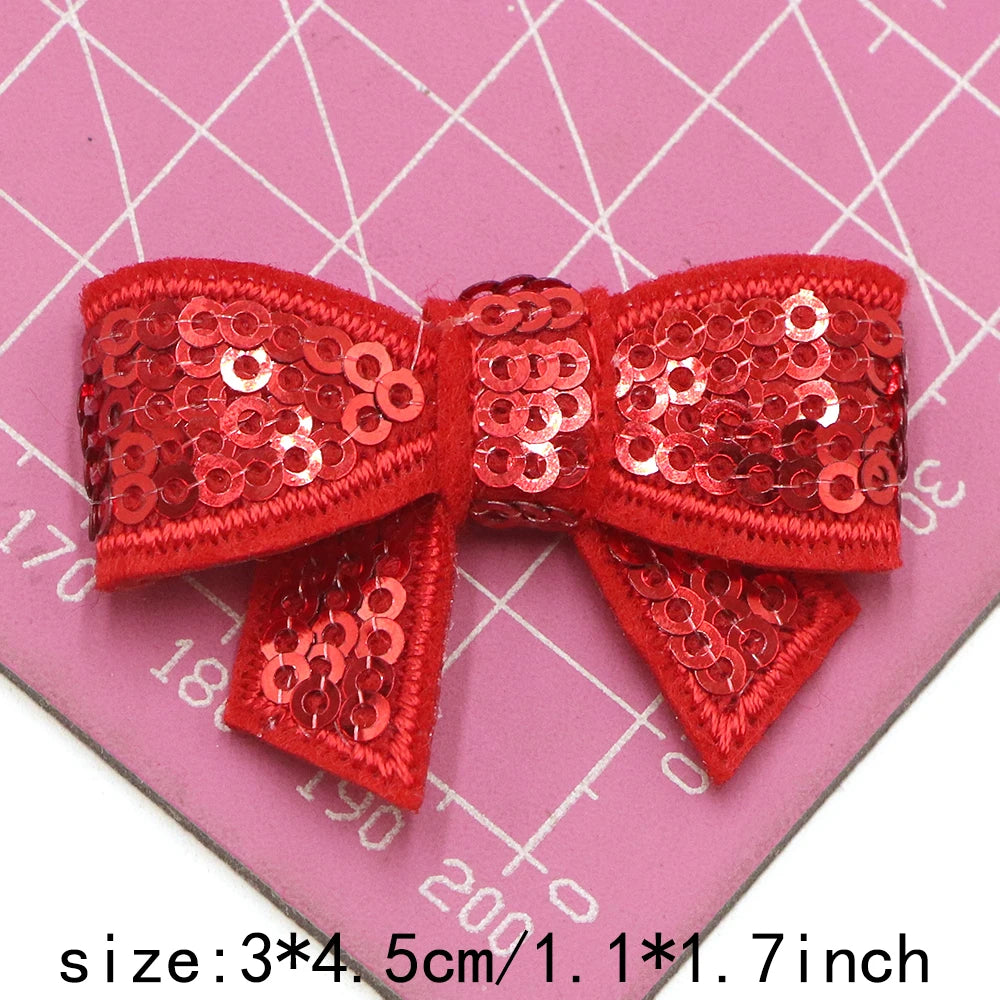Red sequin bow patches for DIY decoration shown on a pink grid background