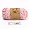 A skein of pink sweet candy yarn with a brown label is shown lying horizontally.