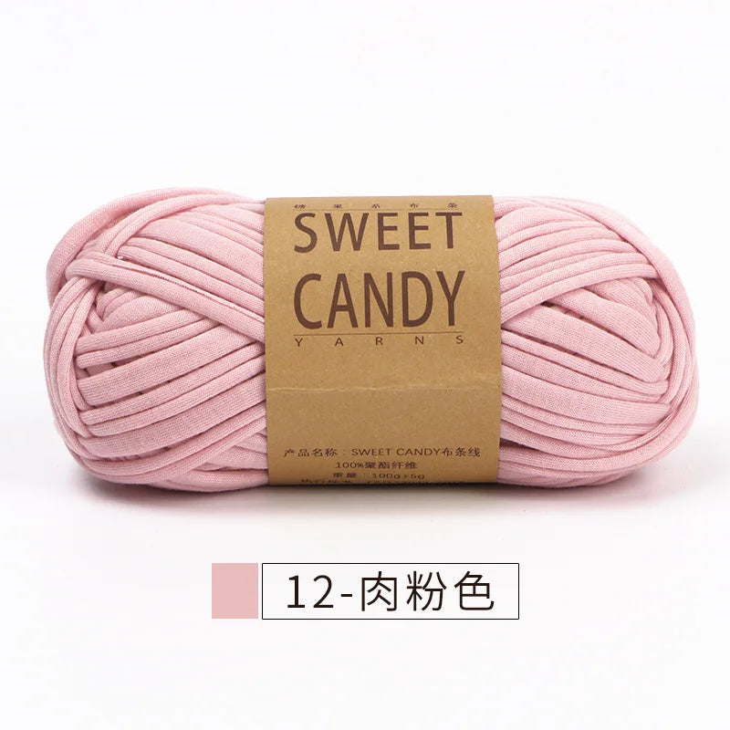 A skein of pink sweet candy yarn with a brown label is shown lying horizontally.